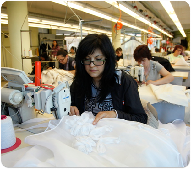 Woman on industrial sewing machine sewing high-end garment.