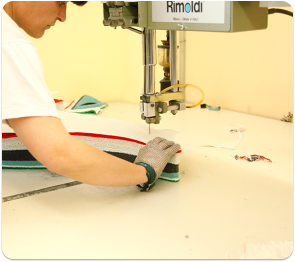 Employee at Mirage uses a Band Knife Cutting Machine for precision fabric cutting in CMT production.